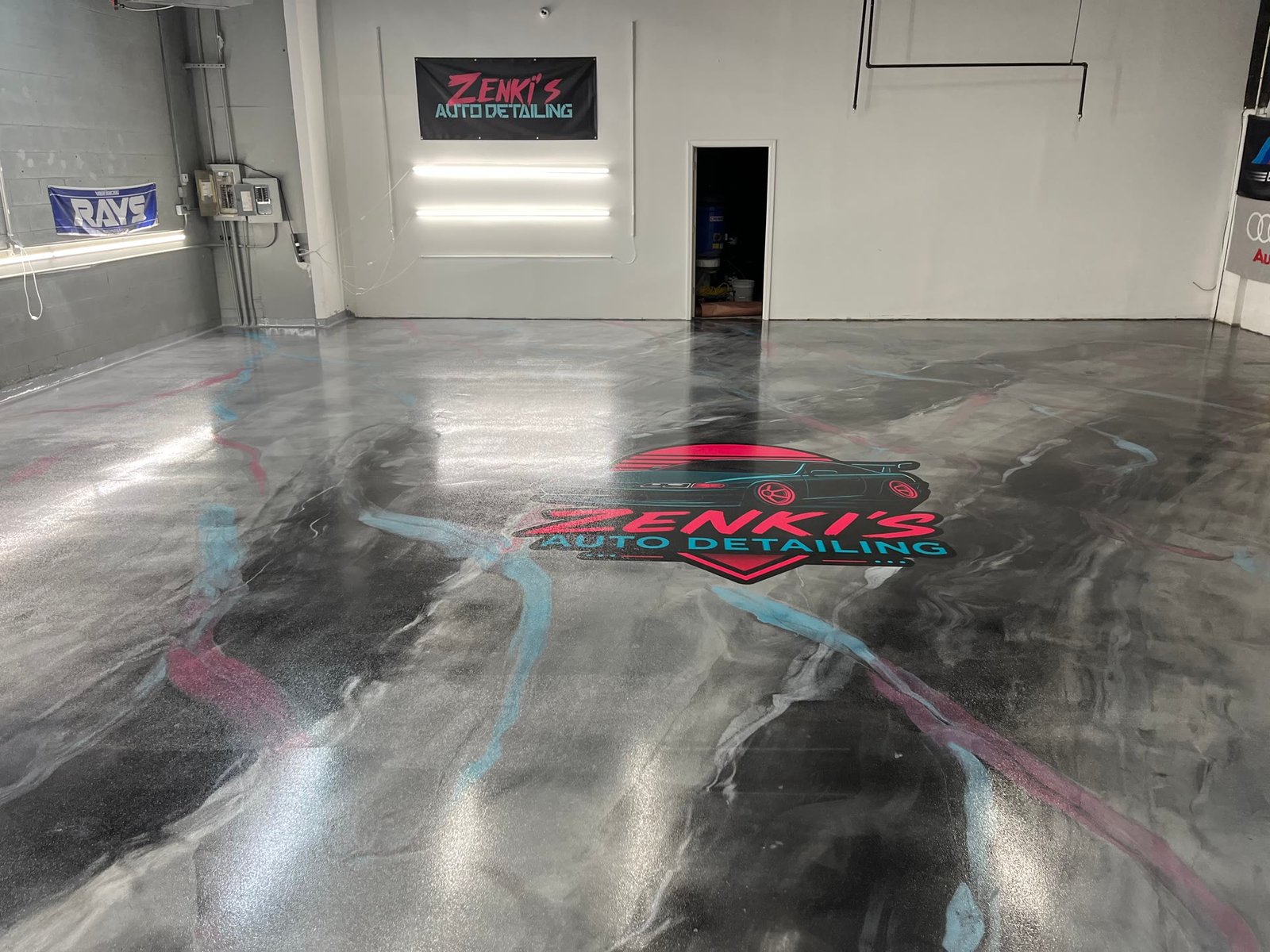 A custom shop logo inlaid into a metallic marbled epoxy floor